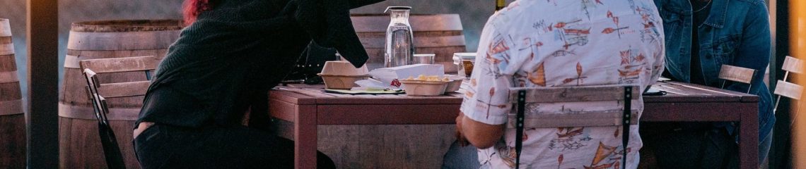 Friends share Urban Legend wine at the winery patio in Alameda, CA with the San Francisco skyline in the background.
